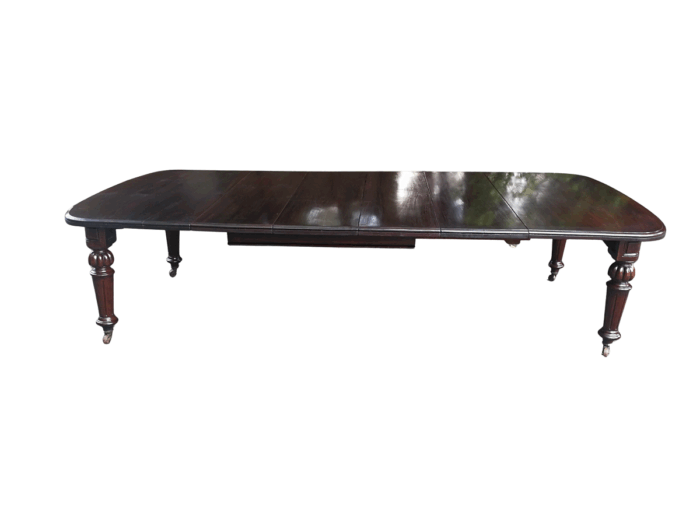 A three meter Victorian mahogany extending dining table on carved legs and castors, with four leaves and crank