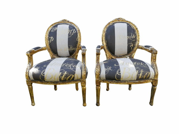 A Pair of French Style Arm Chairs Hand Gilded With Gold Leaf And Upholstered In an Imported Script Fabric