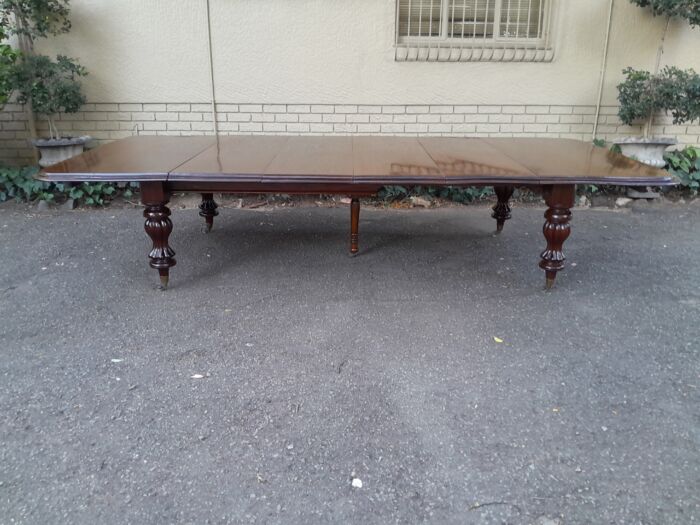 A Massive and Rare Victorian Mahogany Dining / Boardroom Extension table with Four Extensions and Fifth Supporting Leg in the Middle on Original Brass Castors - Image 2