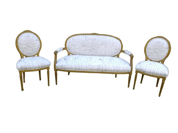An Early 20th Century Set Of French Giltwood Louis XVI Style Settee And Pair of Chairs Upholstered in a Custom-made French Linen Gold Script