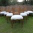 A 20th Century French Set Of Ten Walnut And Rattan Dining Chairs Consisting Of Two Carvers And Eight Dining Chairs Upholstered In A Off-White Linen