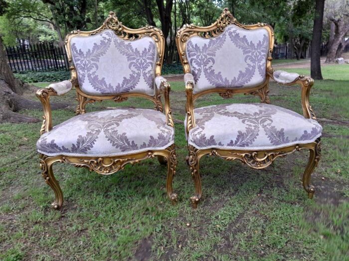 A 20th Century Pair Of French Rococo Style Ornately Carved Wooden Gilt-Wood Arm Chairs