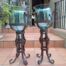 A Pair Of Hurricane Lamps On Wrought Iron Stands With Glass Holders