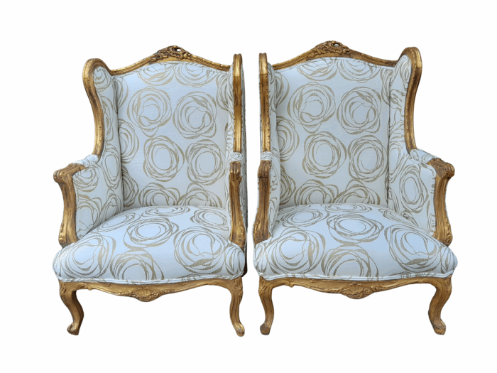 A French Style Pair of Hand Gilded Carved Wingback Chairs Upholstered in a Custom Made for The Crown Collection Cotton / Linen Fabric