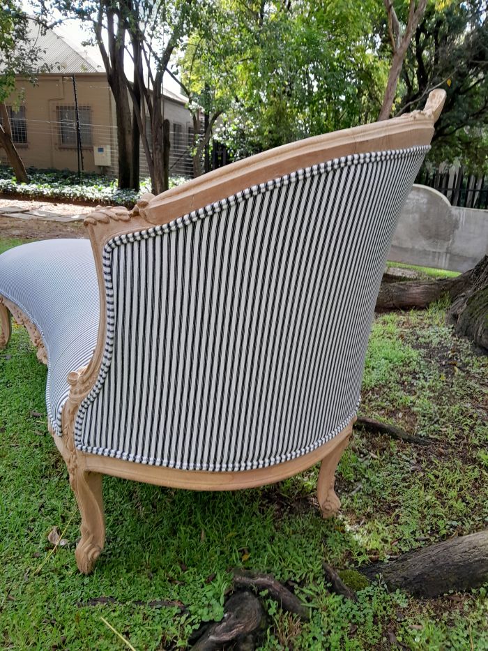 A 20th Century French Style Ornately Carved Chaise Longue in a Contemporary Bleached Finish and Upholstered in Ticking Fabric - Image 8
