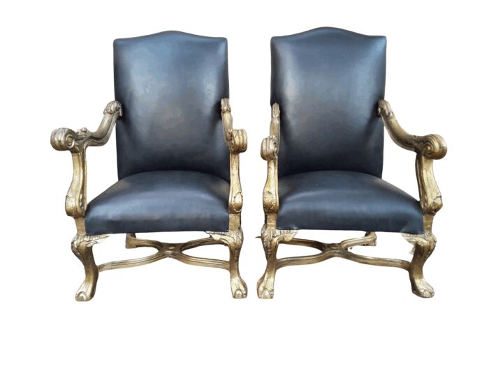 A 20th Century French Style Ornately Carved Pair Of Arm Chairs Hand Gilded And Upholstered In A Deep Buttoned Leather