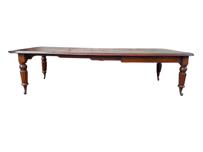 An Antique Edwardian Extending Dining Table with Heavily Carved Legs on Castors and with Crank Handle