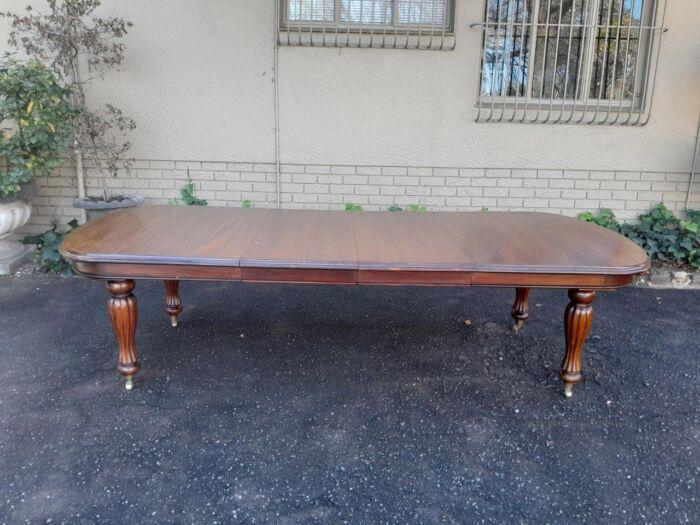 A Massive Antique Circa 1880 Victorian Carved Mahogany Dining Table With Two Extensions On Castors And With Crank Handle - Image 3