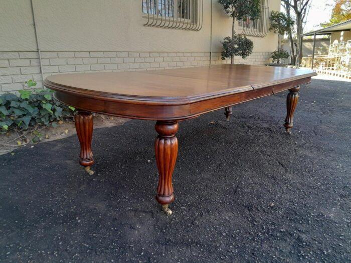 A Massive Antique Circa 1880 Victorian Carved Mahogany Dining Table With Two Extensions On Castors And With Crank Handle - Image 4