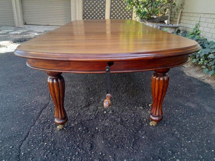 A Massive Antique Circa 1880 Victorian Carved Mahogany Dining Table With Two Extensions On Castors And With Crank Handle - Image 7
