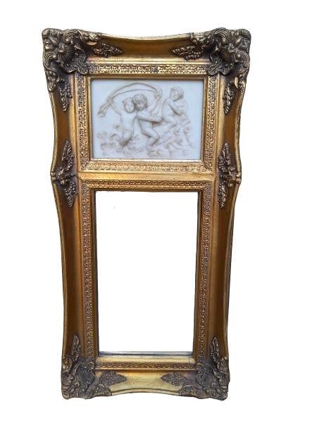 A 20th Century Victorian Style Ornately Carved Giltwood Frame With A Porcelain Style Plaque And Bevelled Mirror