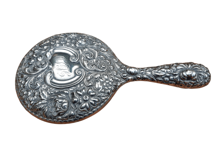 An Antique Repoussé Sterling Silver Hand Held Mirror with signed initials "HDD"