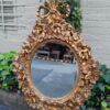 A 20th Century Baroque Style Heavily Carved And Ornate Gilt-Framed Bevelled Glass Mirror