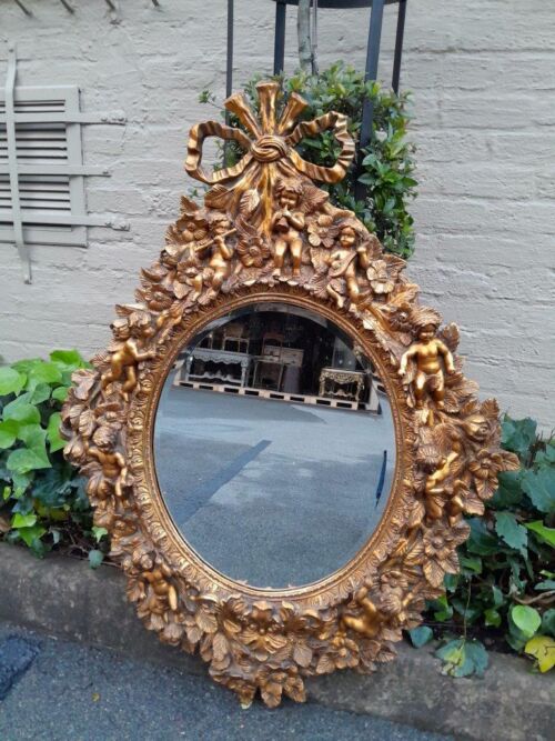 A 20th Century Baroque Style Heavily Carved And Ornate Gilt-Framed Bevelled Glass Mirror